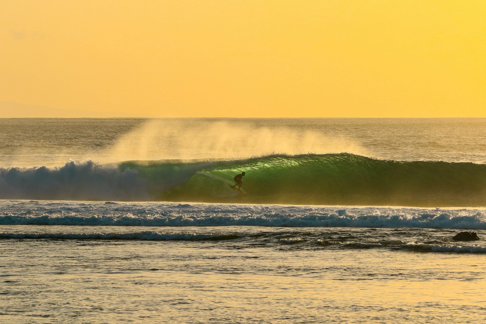 Surfer driving through a green Indonesian wave