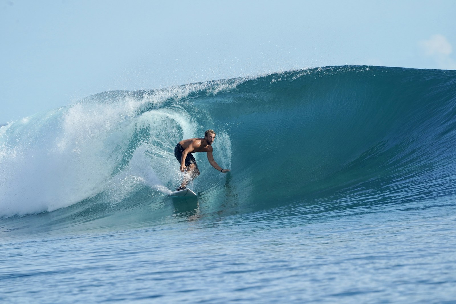 Surfer riding a turquoise barrel in the Mentawai Islands