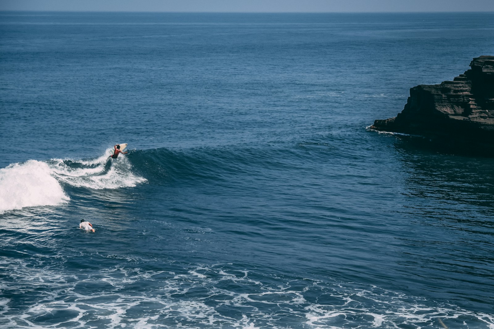 Surfer drawing a high line on an Indonesian reef wave
