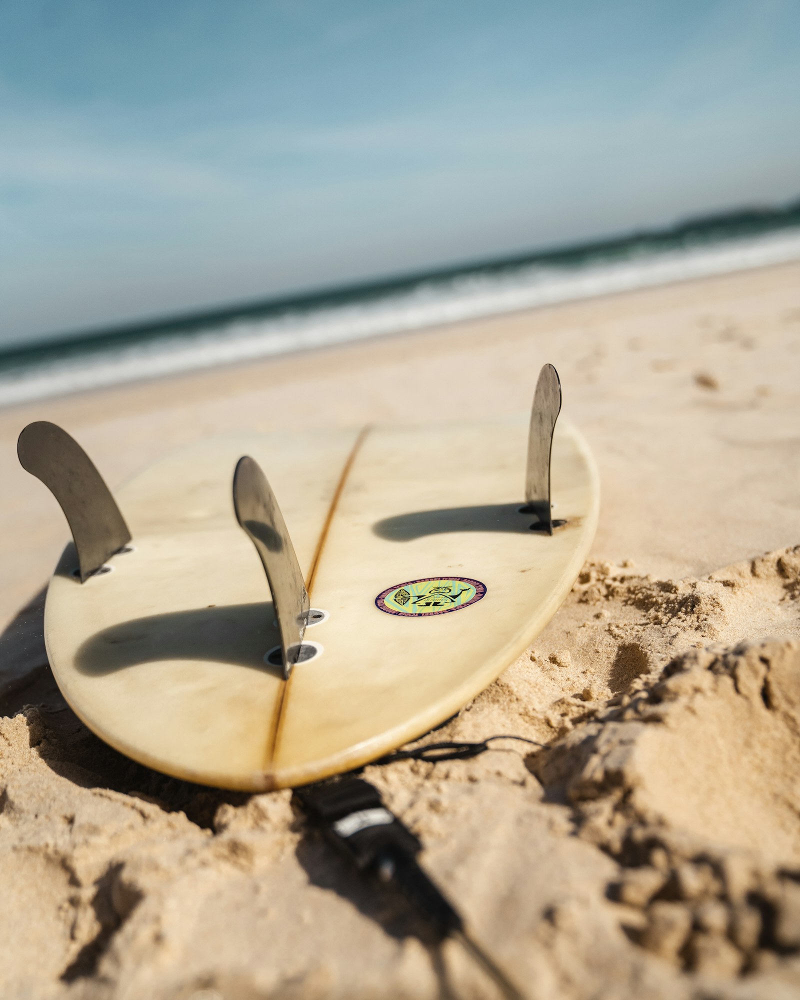 Surfer carrying a board beside Atlantic waves in Portugal